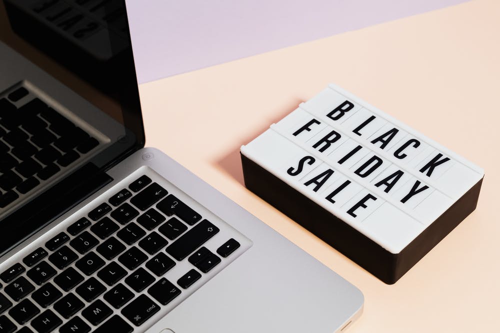 Macbook Pro Beside A Black Friday Sale Sign