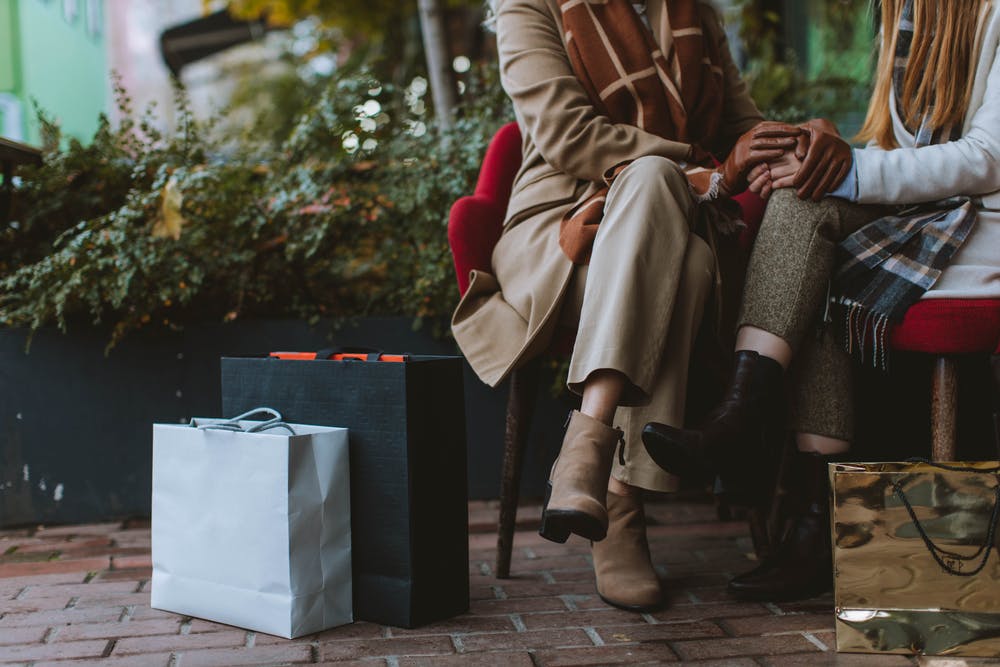 Two Women Sitting On Bench Beside Bags