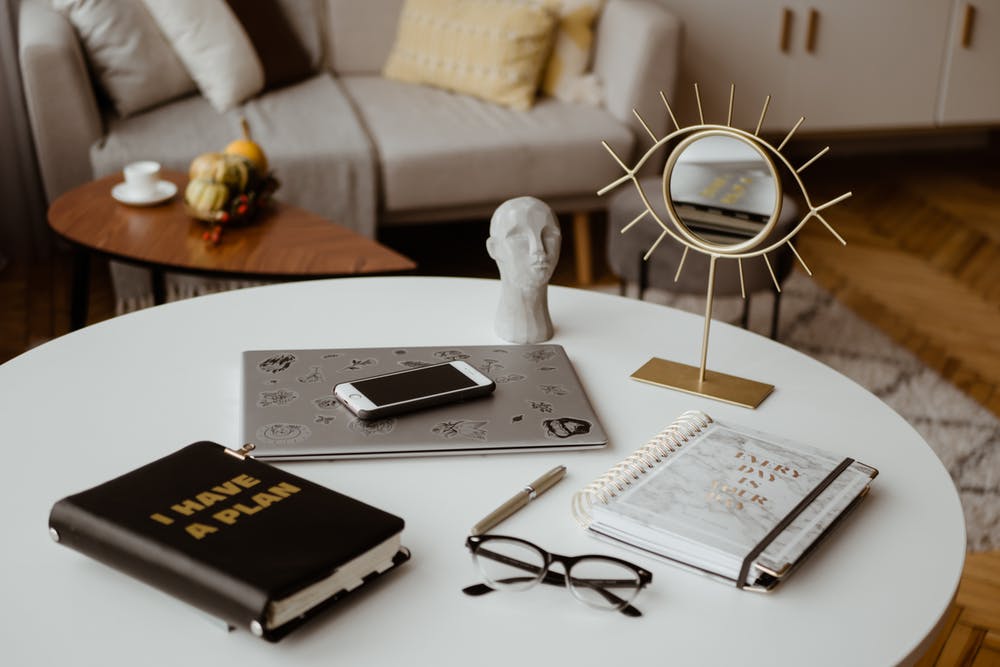 Planner, Notebook, Glasses, Laptop, Mobile Phone & Mirror On A Round Table