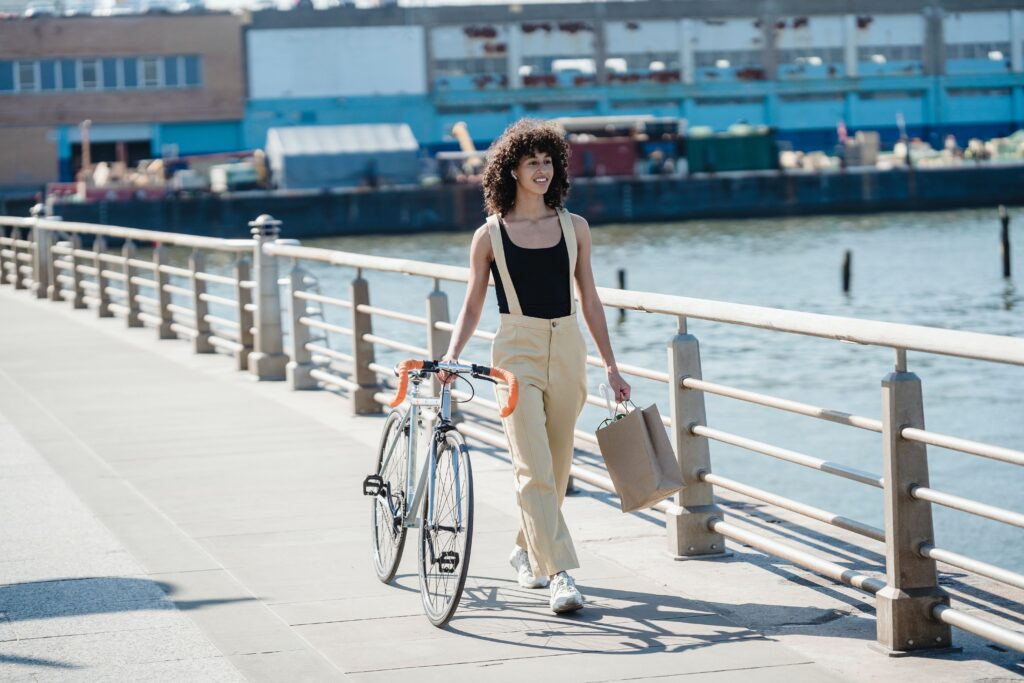 African American female with shopping bag and bicycle on seafront